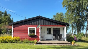 A red and white building with a porch, a flag, and a garden. - Swedish house directly on the lake with motorboat & own boat ramp (Storfors)