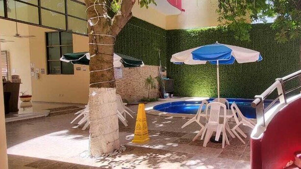 Un espace piscine doté d’un escalier, de sièges extérieurs et d’un parasol.
