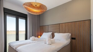 A modern hotel room with a large bed, a wooden headboard, and a balcony view.