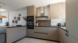 A modern kitchen with beige cabinetry, a stainless steel range hood, and a built-in oven.