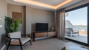 A modern living room with a TV, a sofa, a plant, and a balcony with a view.