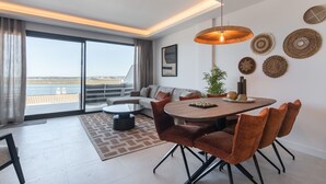 A modern living room with a large window, a round dining table, and a sofa.