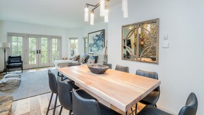 A spacious dining area with a long wooden table, black chairs, and a modern chandelier. - Westermere 211 - The Pinecone (Mountain Village)