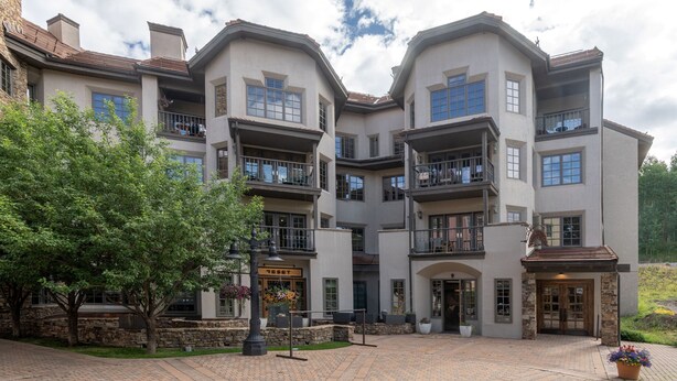 A multi-story building with balconies, a stone facade, and a paved courtyard. - Westermere 211 - The Pinecone (Mountain Village)