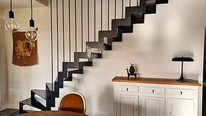 Ein modernes Interieur mit einer schwarzen Treppe, einem Holzesstisch und einem weißen Schrank mit Schubladen.