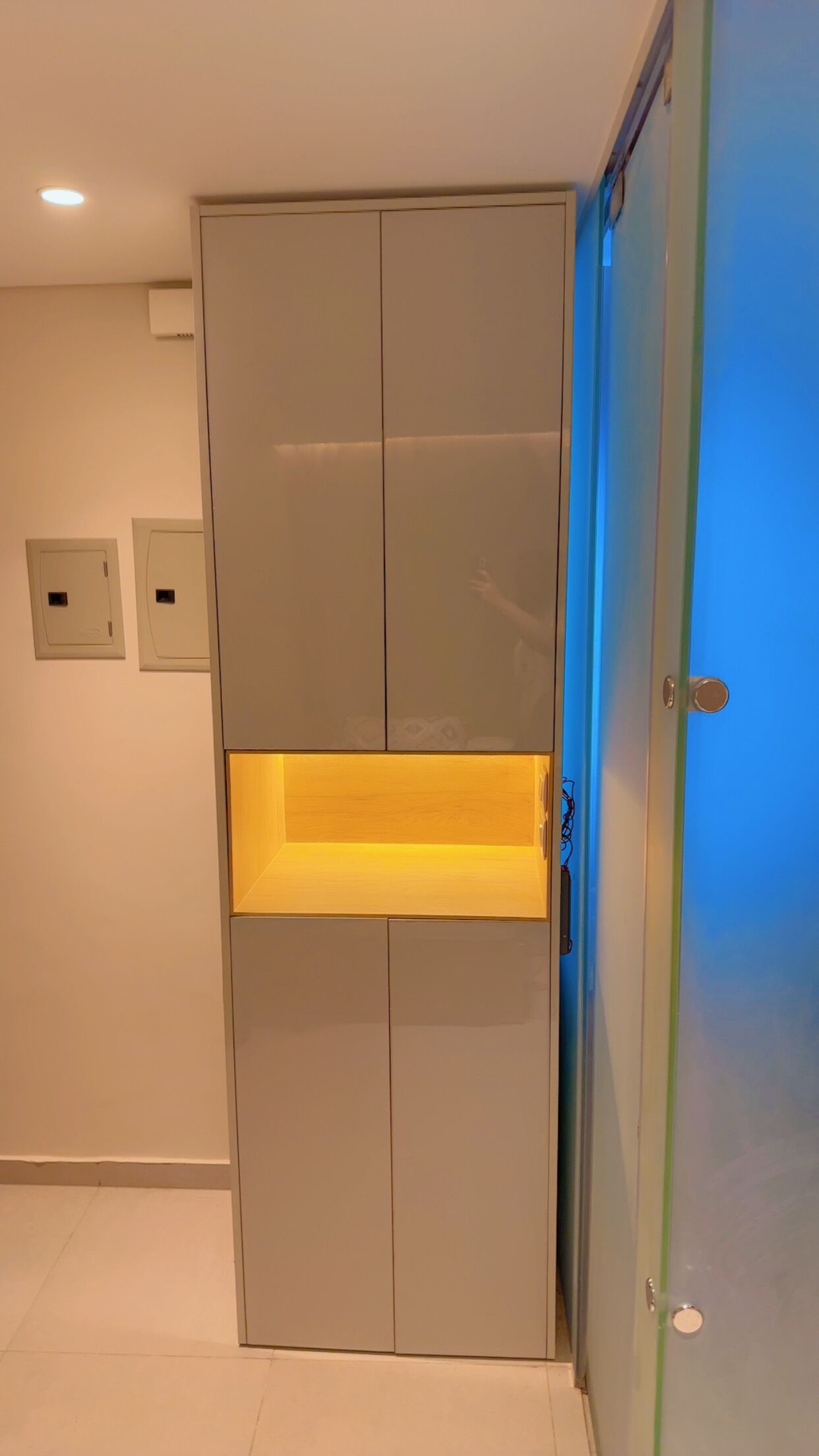 A room with a grey wardrobe, a blue door, and a recessed ceiling light.