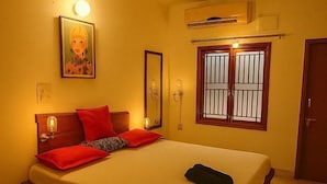 Une chambre à coucher avec un lit, des lampes de chevet, un ventilateur de plafond, une fenêtre avec des barreaux et une porte.