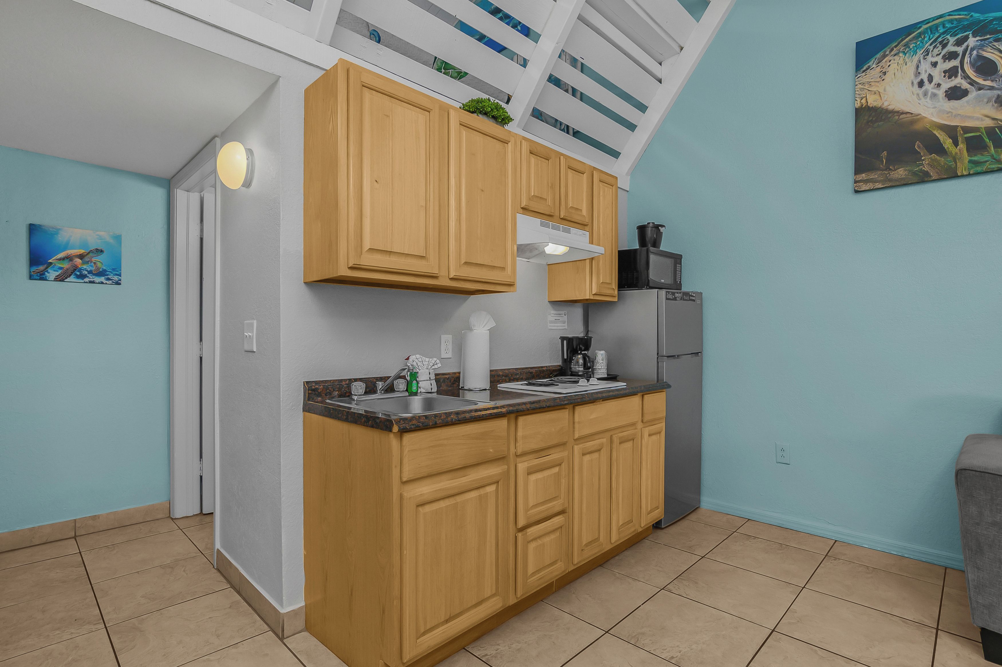 A kitchen with wooden cabinets, a countertop, a microwave, and a refrigerator.
