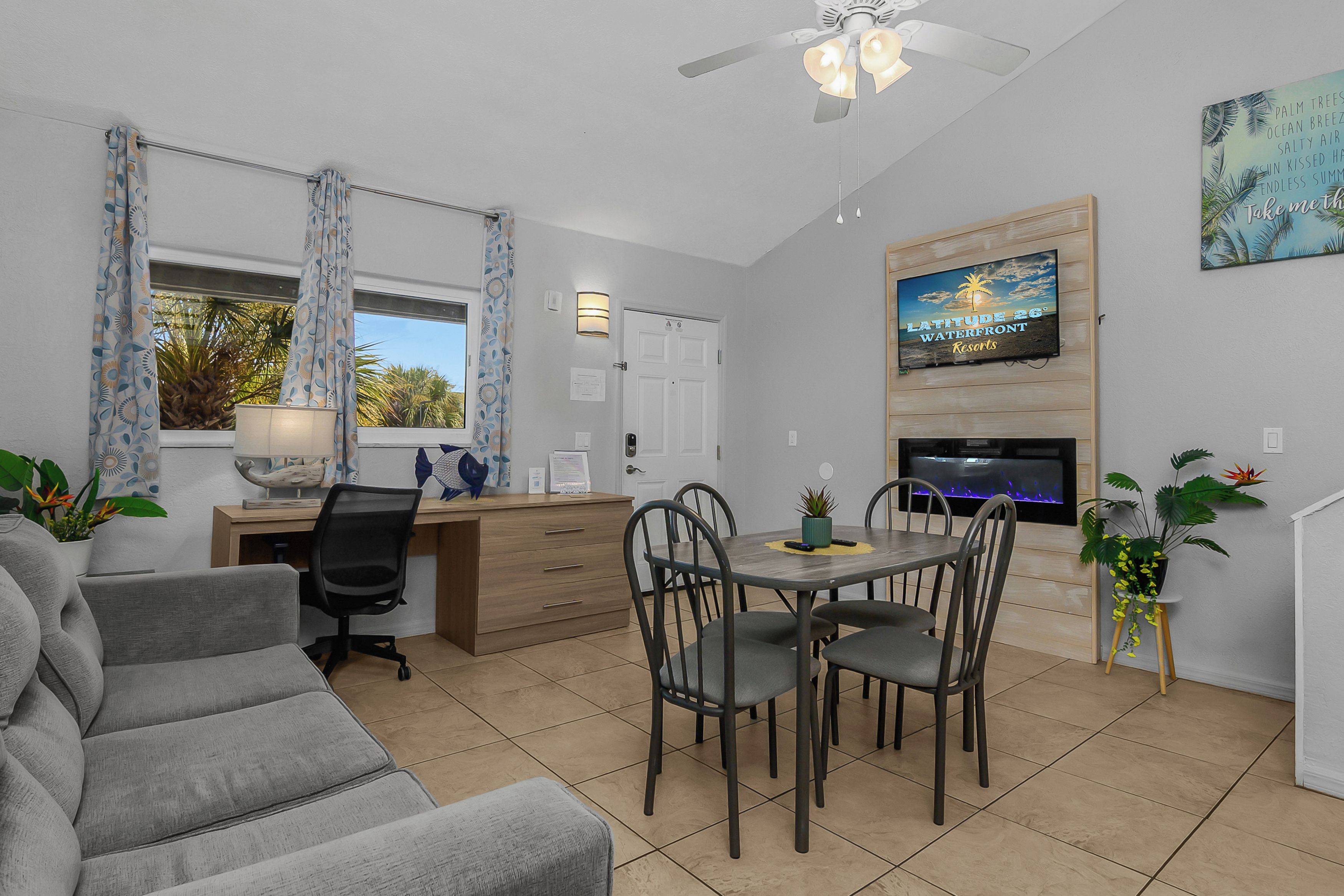 A modern living room with a sofa, dining table, chairs, a TV, and a fireplace.