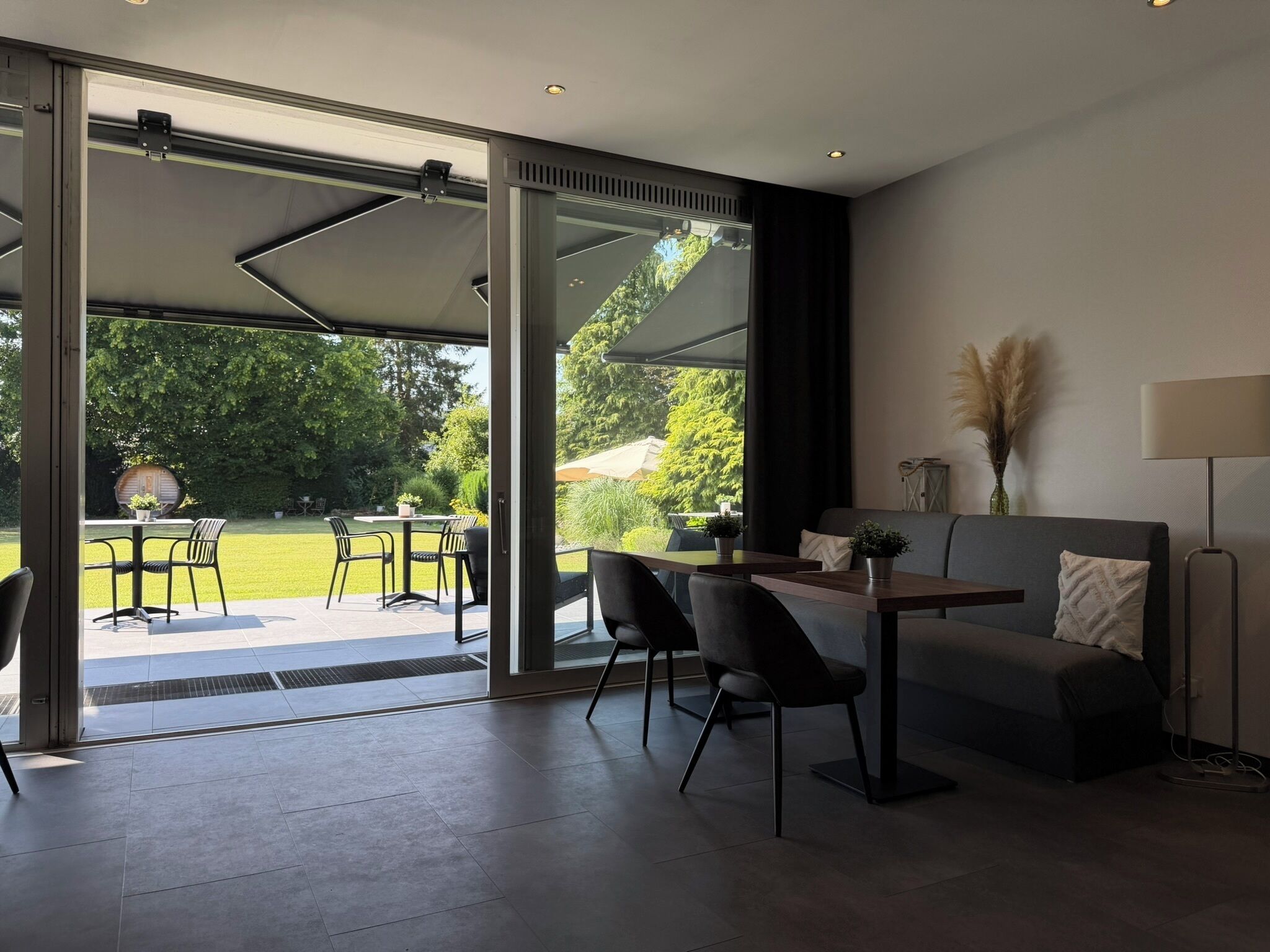 A modern living space with a glass door leading to an outdoor patio, a sofa, a table, and chairs.