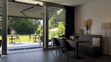 A modern living space with a glass door leading to an outdoor patio, a sofa, a table, and chairs.
