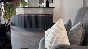 Un salon moderne avec un canapé gris, une table basse en bois et un vase noir orné de fleurs.