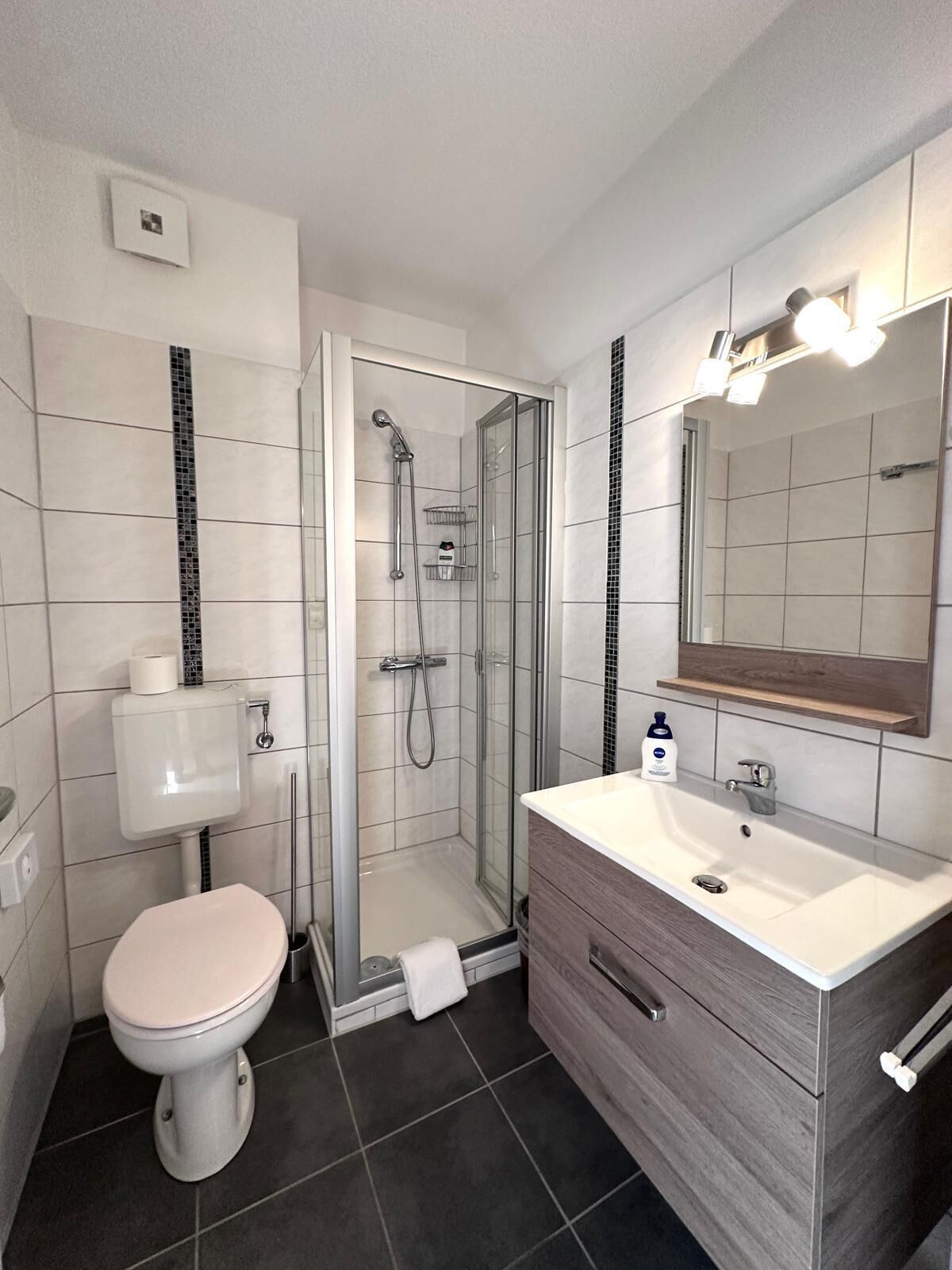 Un baño moderno con inodoro, lavamanos y ducha.