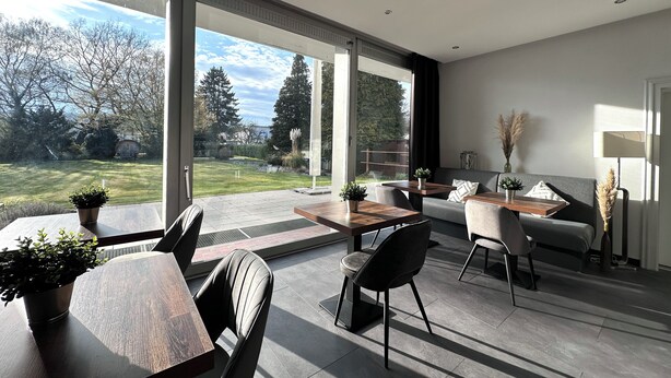 Un salon moderne comprenant un coin repas, de grandes fenêtres et une vue sur un jardin.