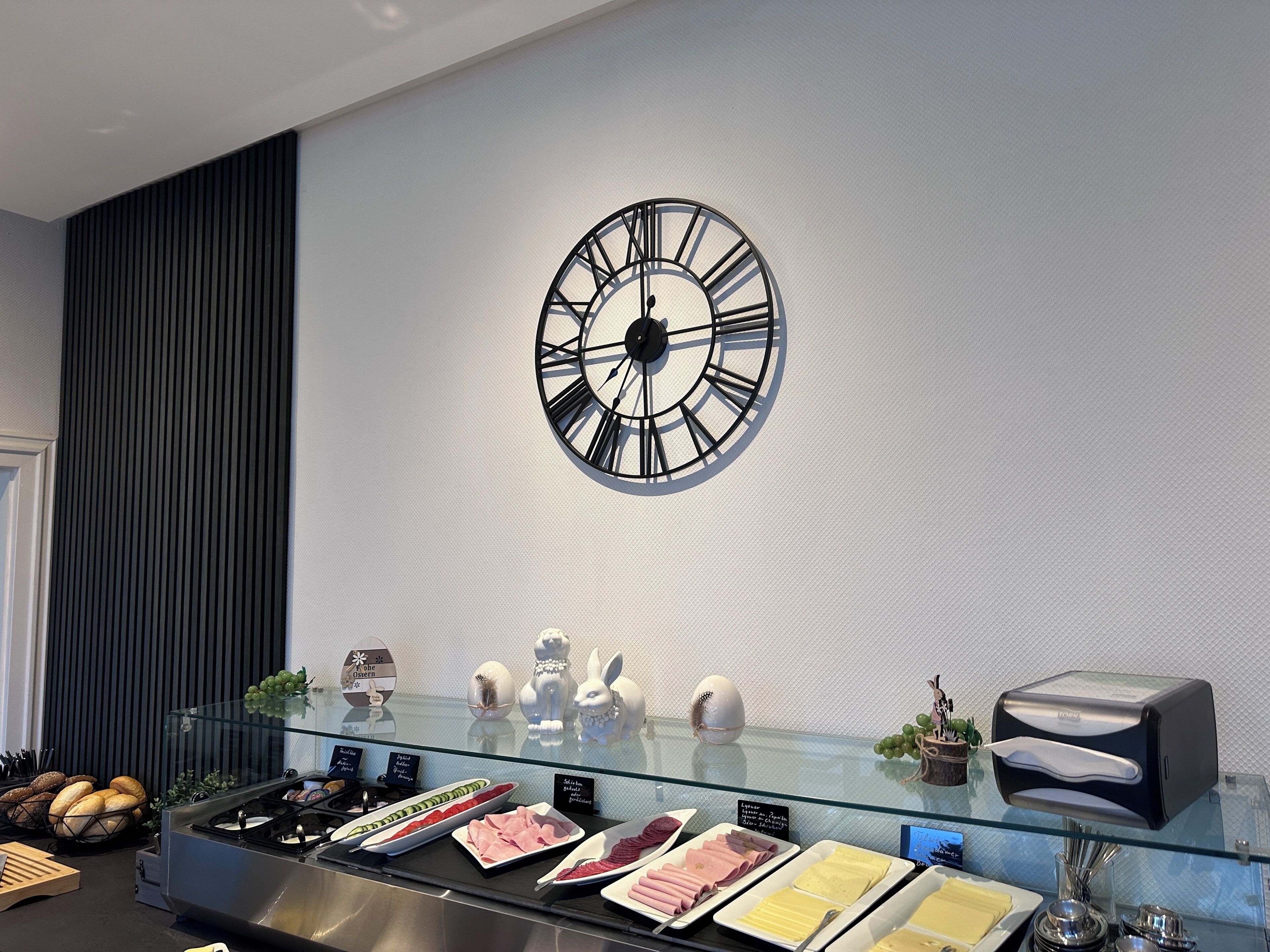 A breakfast buffet with various food items, a clock on the wall, and a modern interior design.