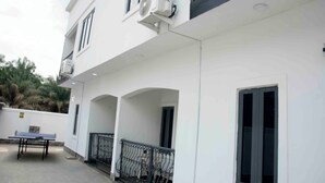 A modern building with a balcony, a table, and a window. - Slim Anyaiwe Apartments (Agbor)