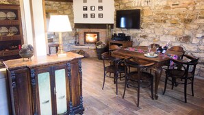 A cozy dining area with a stone fireplace, wooden furniture, and a flat-screen TV mounted on the wall. - Located in the mountains, in Lierganes and close to the beach. Pets are allowed. (Lierganes)