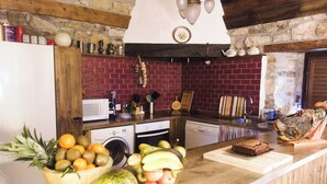 A kitchen with a stone wall, wooden beams, a white refrigerator, a microwave, a sink, and various kitchen utensils. - Located in the mountains, in Lierganes and close to the beach. Pets are allowed. (Lierganes)