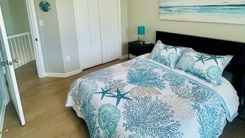 A bedroom with a bed, a nightstand, a door, and a wall with a painting.