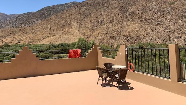 Una terraza con mobiliario de mimbre y vistas a un paisaje montañoso.