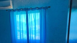 Una habitación con cortina azul, ventana y aire acondicionado.