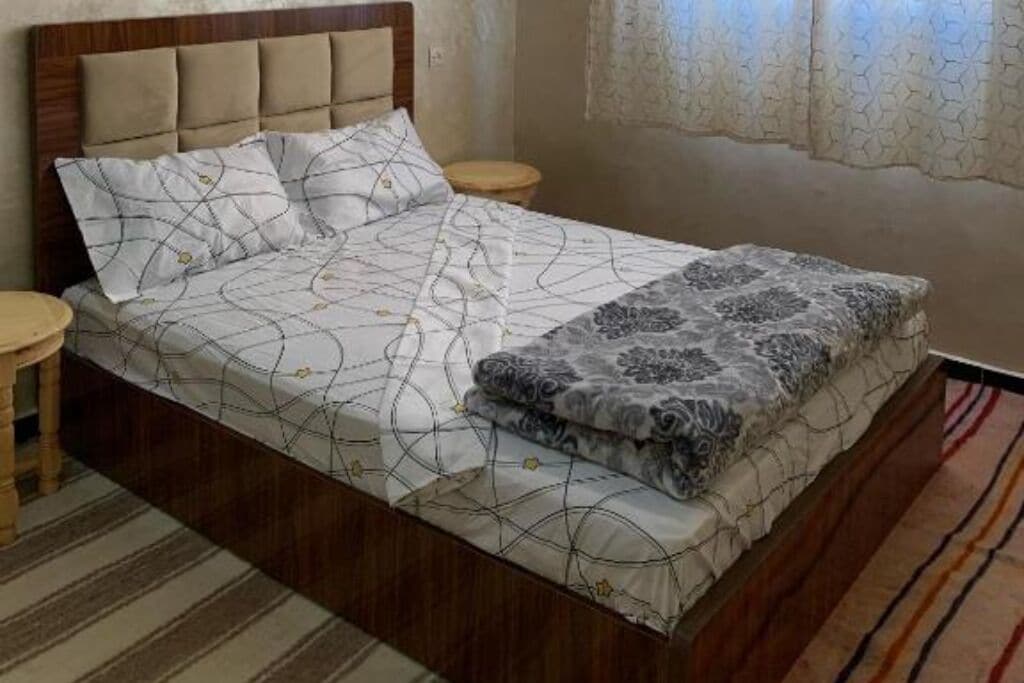 A neatly made bed with patterned bedding, a wooden headboard, and two bedside tables.