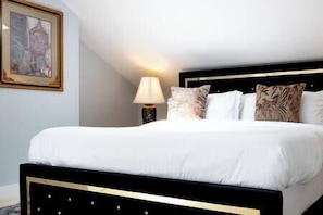 A neatly made bed with a black headboard, white bedding, and decorative pillows.