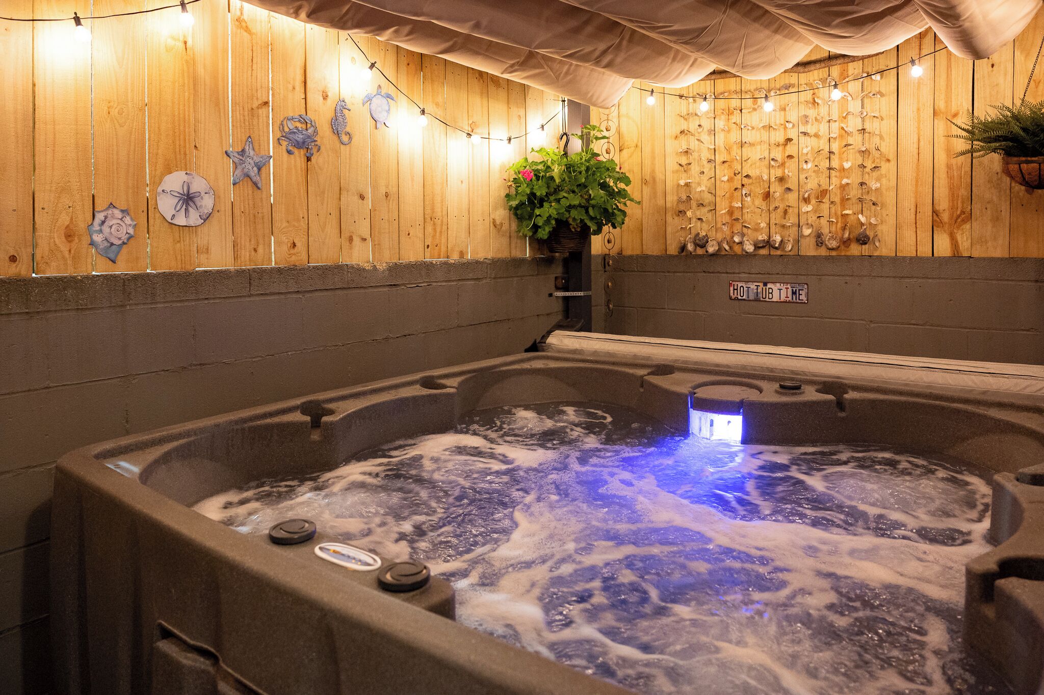 Uma banheira de hidromassagem com água borbulhante, rodeada por paredes de madeira e conchas decorativas.