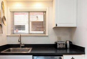 A kitchen with a window, a sink, a toaster, and cabinets.