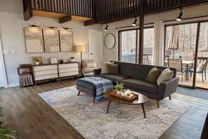 Uma sala de estar moderna com sofá, banquinho, mesa de centro e obras de arte na parede.