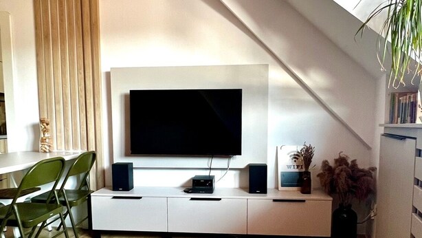 A modern living room with a flat-screen TV, a white entertainment unit, a geometric-patterned rug, and a wooden floor. - Cozy Flat in Villa Near Old Town (București)