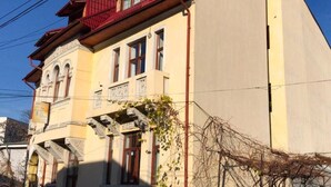A multi-story building with a yellow facade, red roof, and ornate balconies. - Cozy Flat in Villa Near Old Town (București)