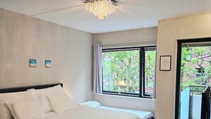 A bedroom with a bed, a desk, a chandelier, and a window with a view of greenery. - Cozy & Central studio in the royal heart of Oslo (Oslo)