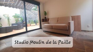Un studio avec une porte-fenêtre coulissante donnant sur un patio.