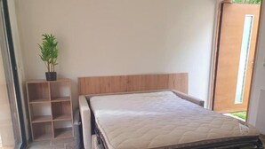 Une pièce comprenant un lit, une tête de lit en bois, une plante en pot et une porte coulissante.