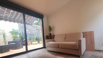 Un studio avec une porte-fenêtre coulissante donnant sur un patio.