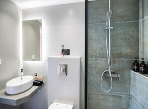 Un baño moderno con lavamanos, inodoro y ducha blancos.