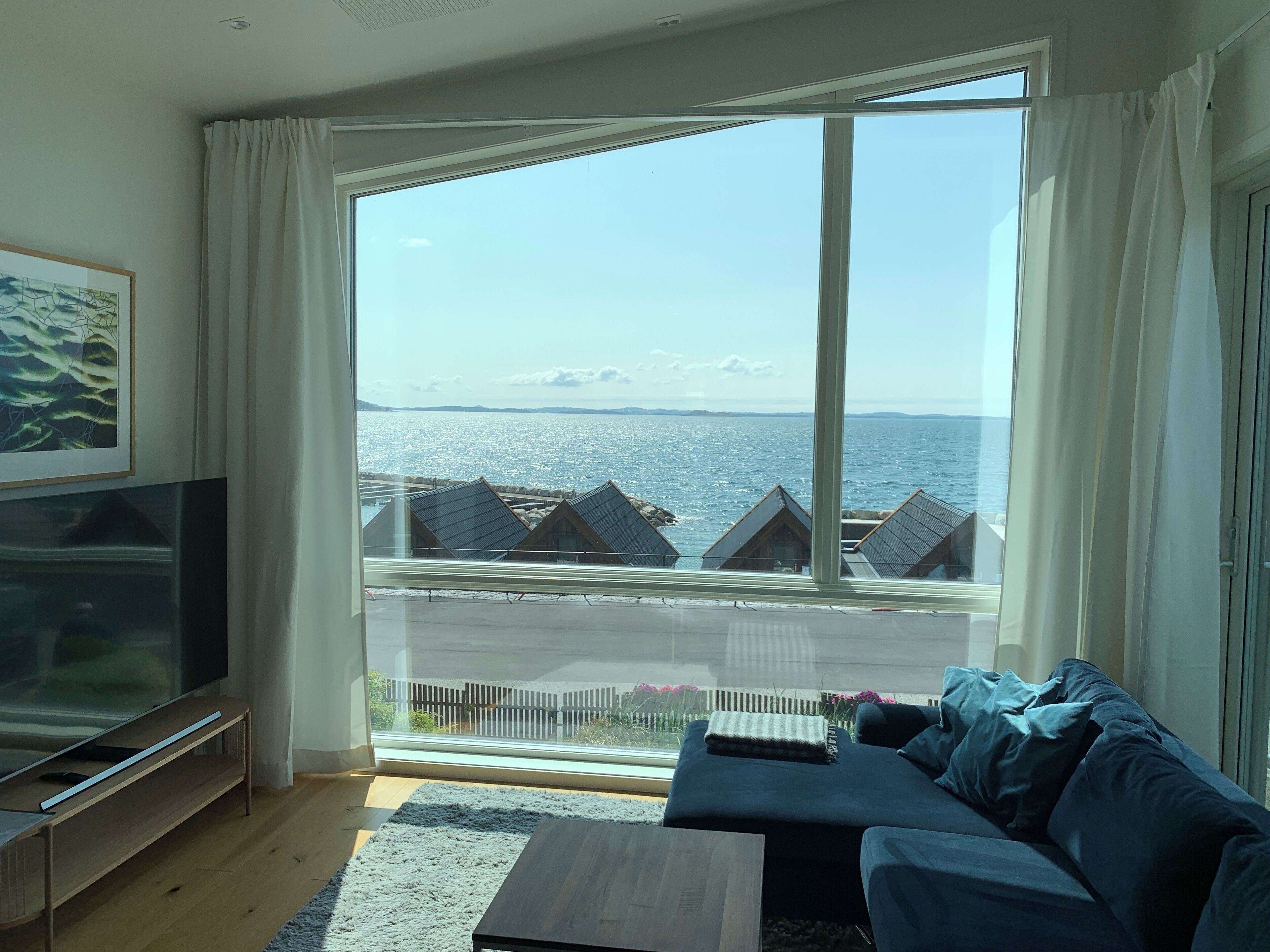 A living room with a large window, a television, and a sofa.