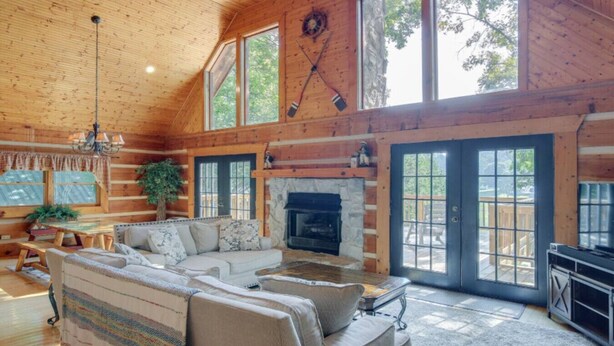 Een houten chalet interieur met een ruime woonkamer, open haard en grote ramen.