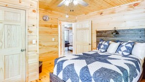 Ein Schlafzimmer einer Holzhütte mit einem Bett, einem Deckenventilator und einer Uhr an der Wand.