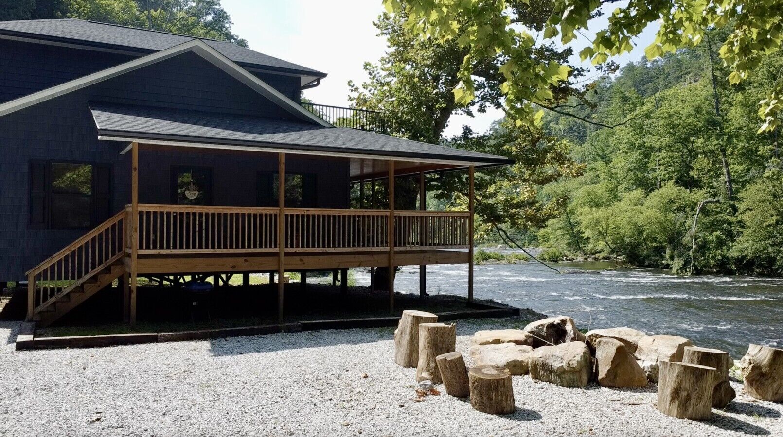 A cabin with a wooden deck and a river view.