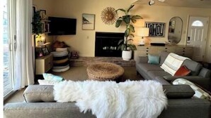 A living room with a sofa, a fluffy white throw, a sun decoration, a television, and a fireplace. - Unique Home on Peaceful Waterfront (Stafford Township)