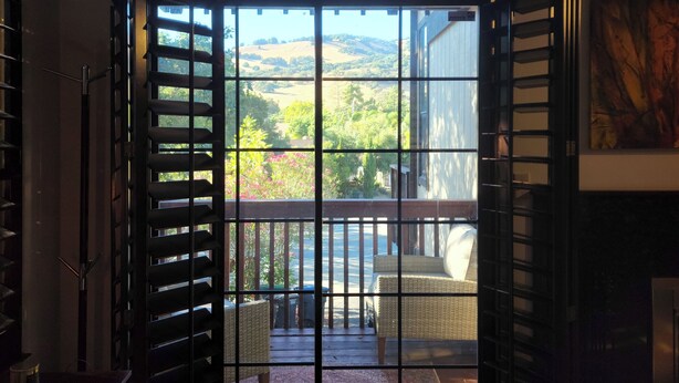 A hotel room with a large sliding glass door leading to a balcony with outdoor seating and a view of the countryside. - High-End Private Suite with Deck & Mountain Views in Prime Marin County Location (Novato)