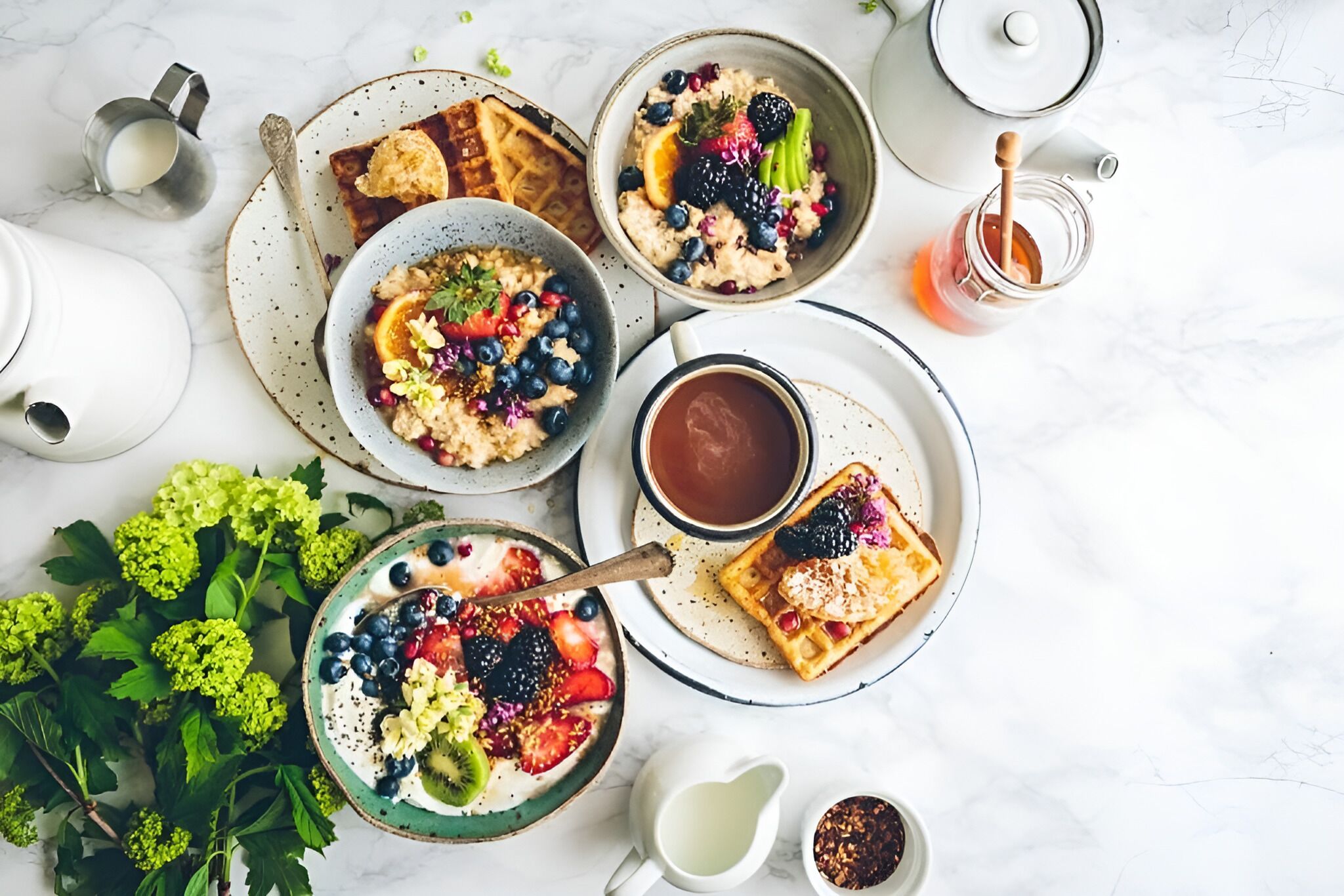 A breakfast setting with waffles, fruit, and coffee on a marble surface.