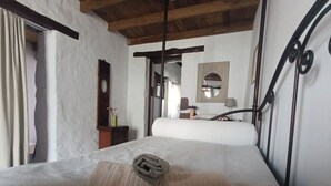 Un dormitori amb un llit, un panell de fusta al capçal, una tauleta de nit, un mirall i una finestra.