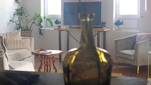 Un saló amb un sofà, una taula de centre, una televisió i un ram de flors.