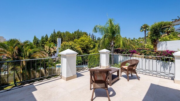 A balcony with two wicker chairs and a small table, surrounded by a metal railing and white pillars. - Luxury villa in the center of Marbella (Marbella)