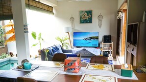 Un soggiorno con televisione, un laptop e un'area pranzo con tavolo apparecchiato per due persone.