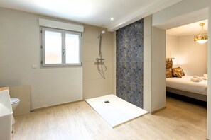 Un baño moderno con ducha, inodoro y una cama con almohadas.