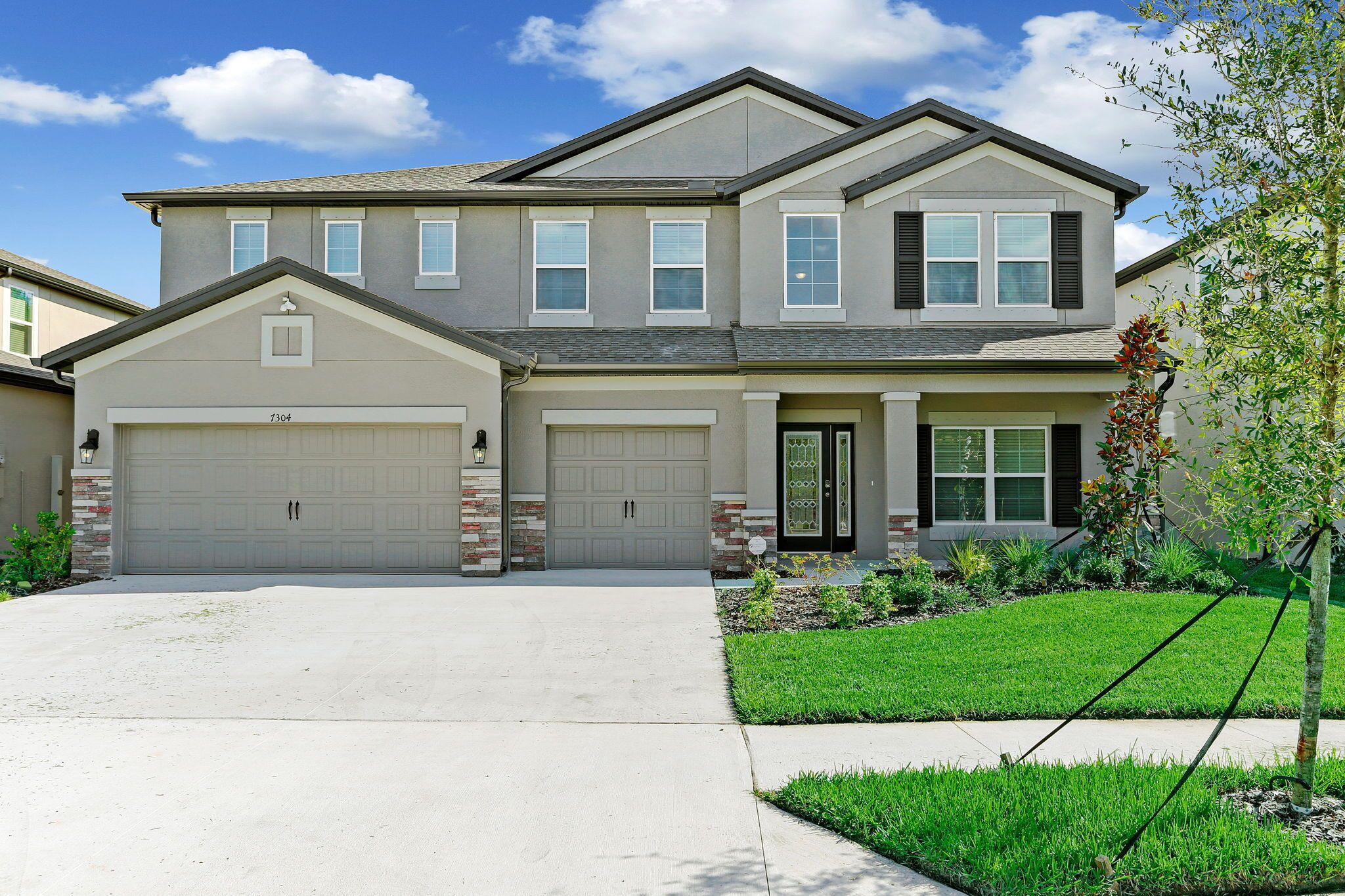A two-story house with a garage, a front door with a decorative glass panel, and a well-maintained lawn.